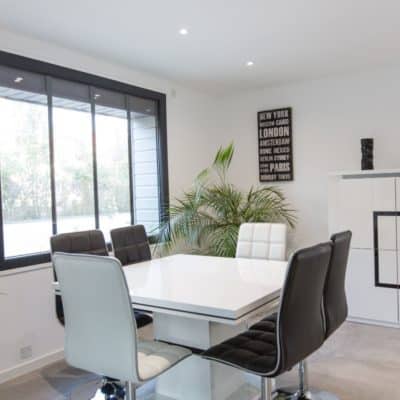 Salle à manger moderne blanche et noire, avec un fenêtre en PVC gris anthracite et équipée de petis-bois verticaux intégrés.