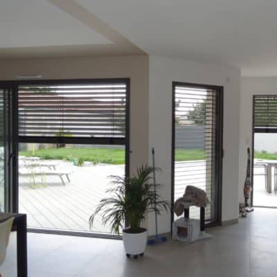 Salle à manger équipée de baies vitrées avec brise soleil orientable semi-fermé.